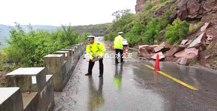白水交警冒雨清理路面落石。