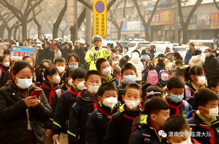 2月6日临渭大队民警用大喇叭指挥小学生有序离校。