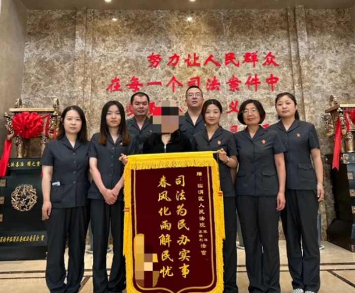 楊某將一面印有“司法為民辦實事 春風化雨解民憂”的錦旗送至民四庭法官蘇瑞利、法官助理陳洋手中。