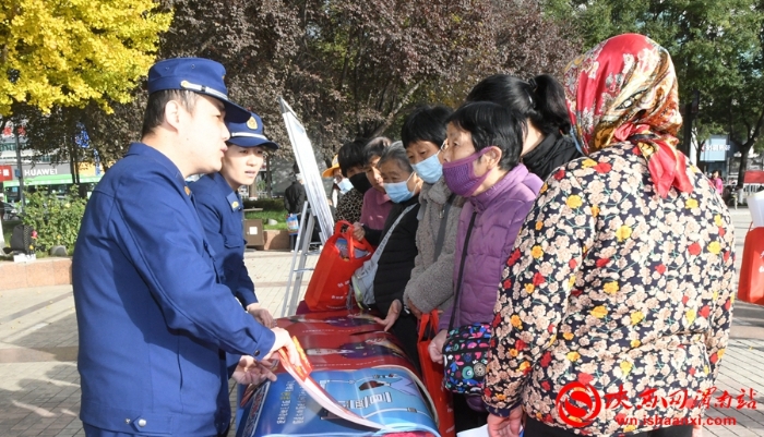 工作人员向过往群众发放平安临渭建设宣传资料、宣传小礼品，并介绍平安建设相关知识。记者 陈冰娟 摄