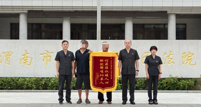 案件当事人赵某走进渭南市临渭区人民法院将一面锦旗送至法官手中。