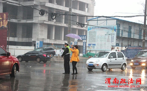 清明节期间，渭南市区东风大街与民生路十字口，瓢泼大雨中执勤疏导的交警，感动了途经此处的市民，一位女士发自内心的为民警撑起爱心伞。