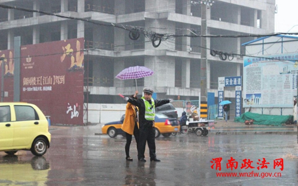 清明节期间，渭南市区东风大街与民生路十字口，瓢泼大雨中执勤疏导的交警，感动了途经此处的市民，一位女士发自内心的为民警撑起爱心伞。